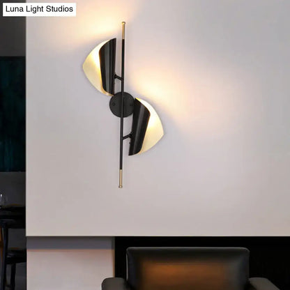 Modern black and brass wall light with two curved illuminated shades for staircase lighting in a postmodern style