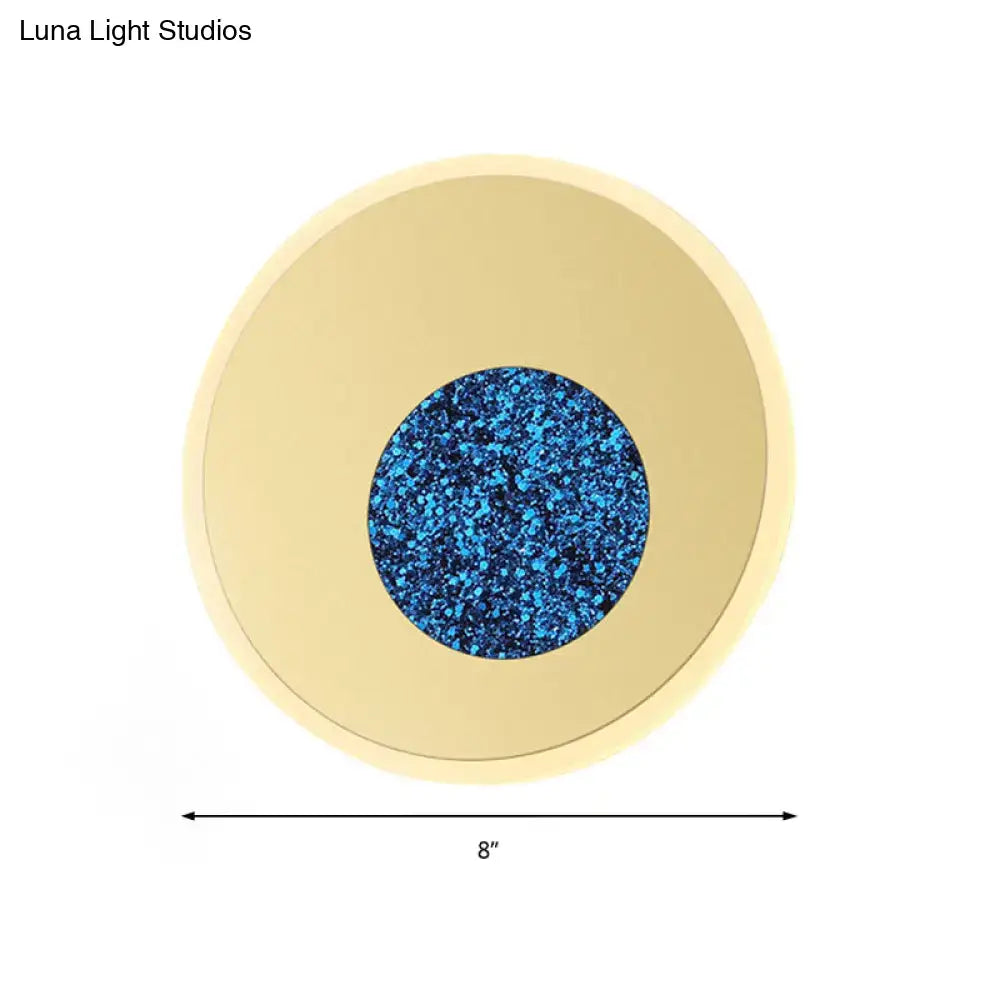 Postmodern blue round sconce light fixture with gold-toned ring and vibrant blue glittery center for bedroom wall use