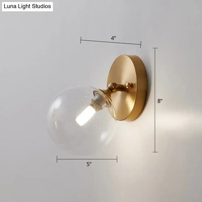 Postmodern brass and glass gold-toned wall sconce with clear globe and bulb included light type for bedroom lighting