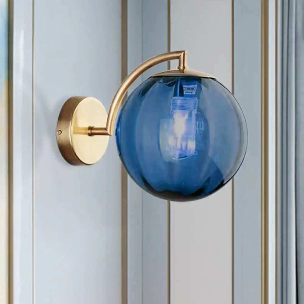 Blue spherical glass ball sconce with brass armed ball metal arm and mounting plate for bedroom wall light