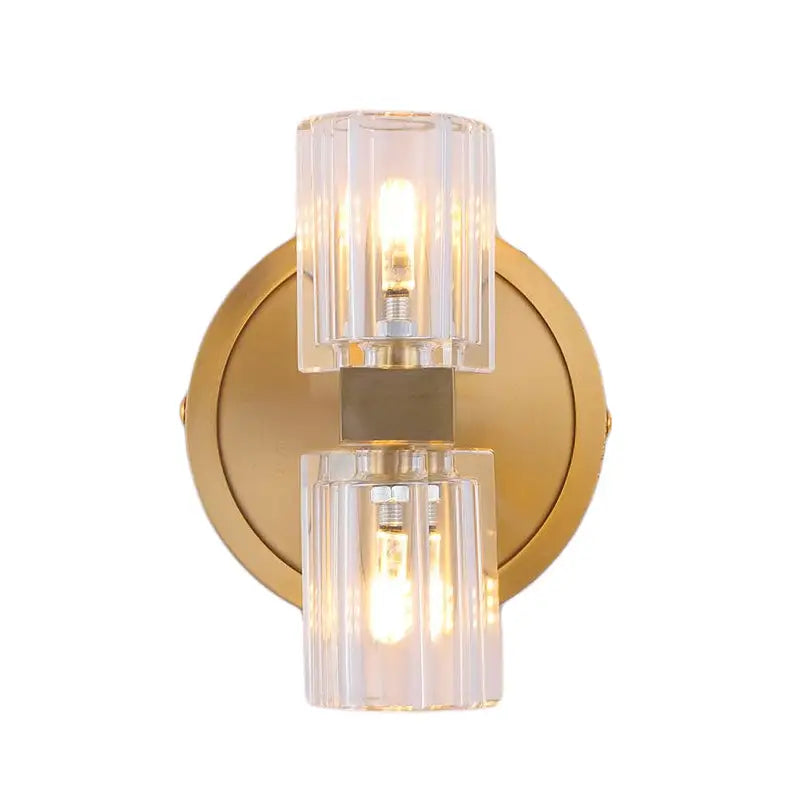 Gold-toned wall light with brass finish and faceted glass crystal cylinders showcasing fixture height in bedroom design