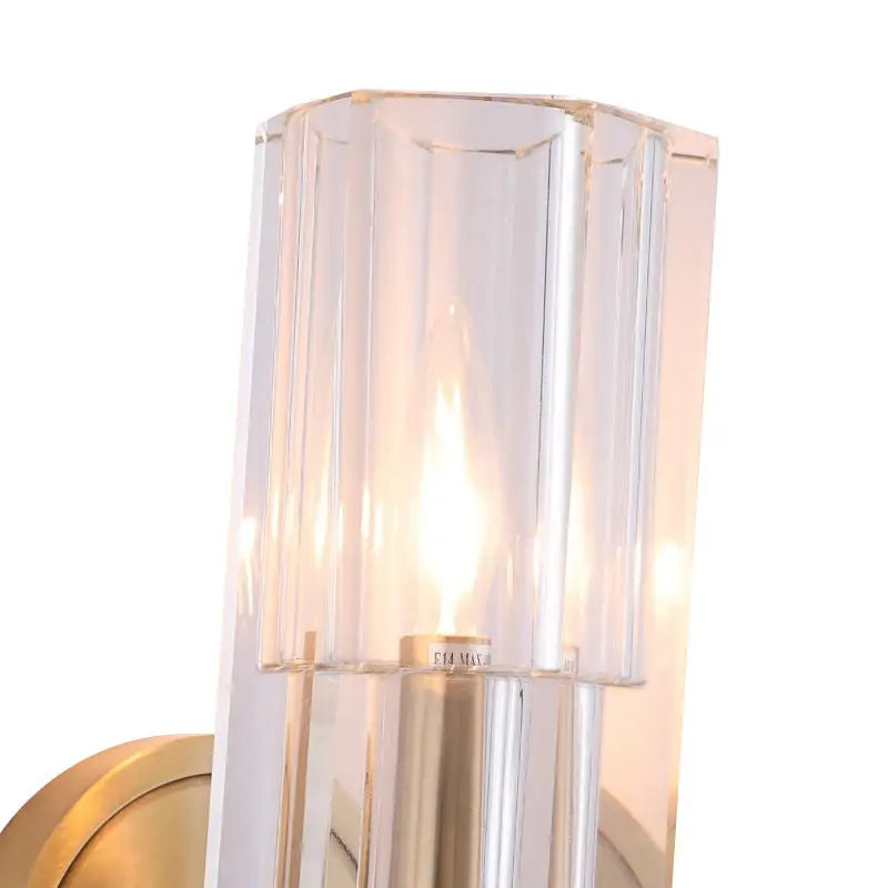 Clear faceted glass wall light with brass finish metal base and stem featuring fixture height for bedroom use