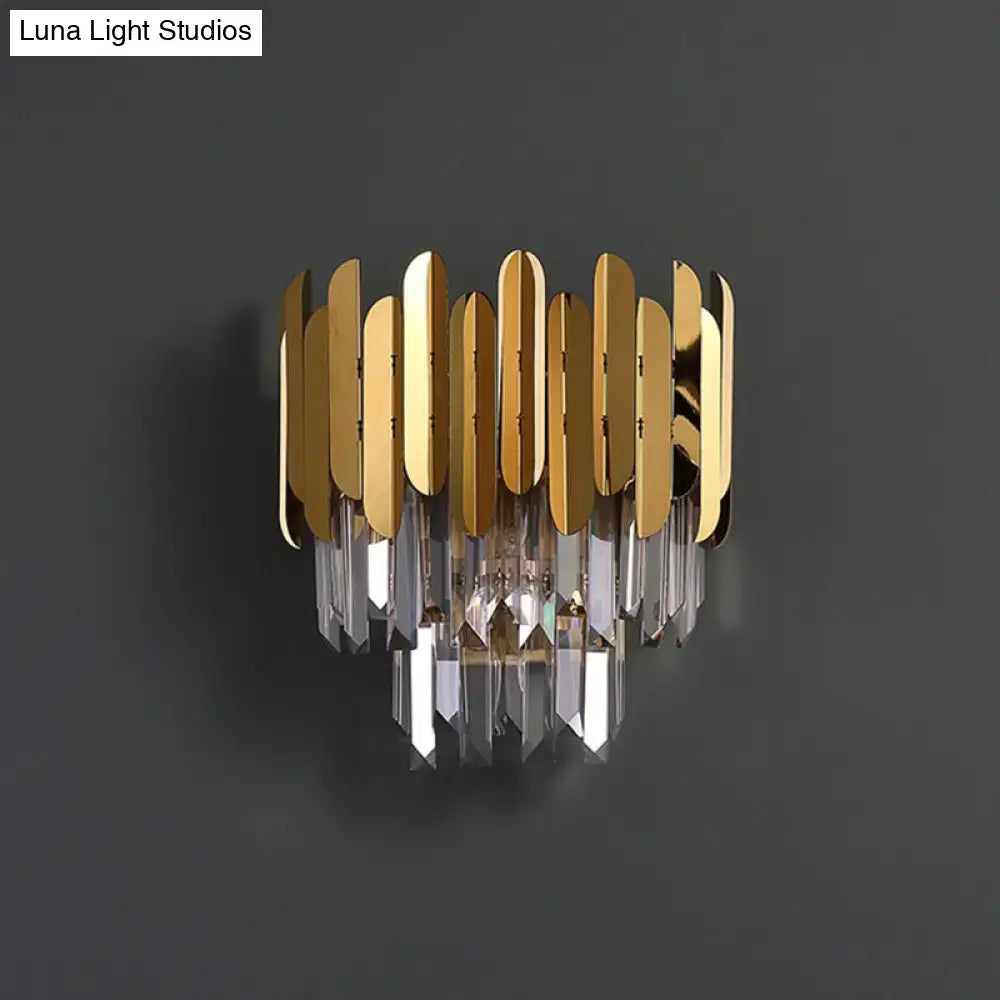 Postmodern brass tiered flush wall sconce with gold-toned vertical metal plates and cascading clear crystal prisms for bedroom lighting