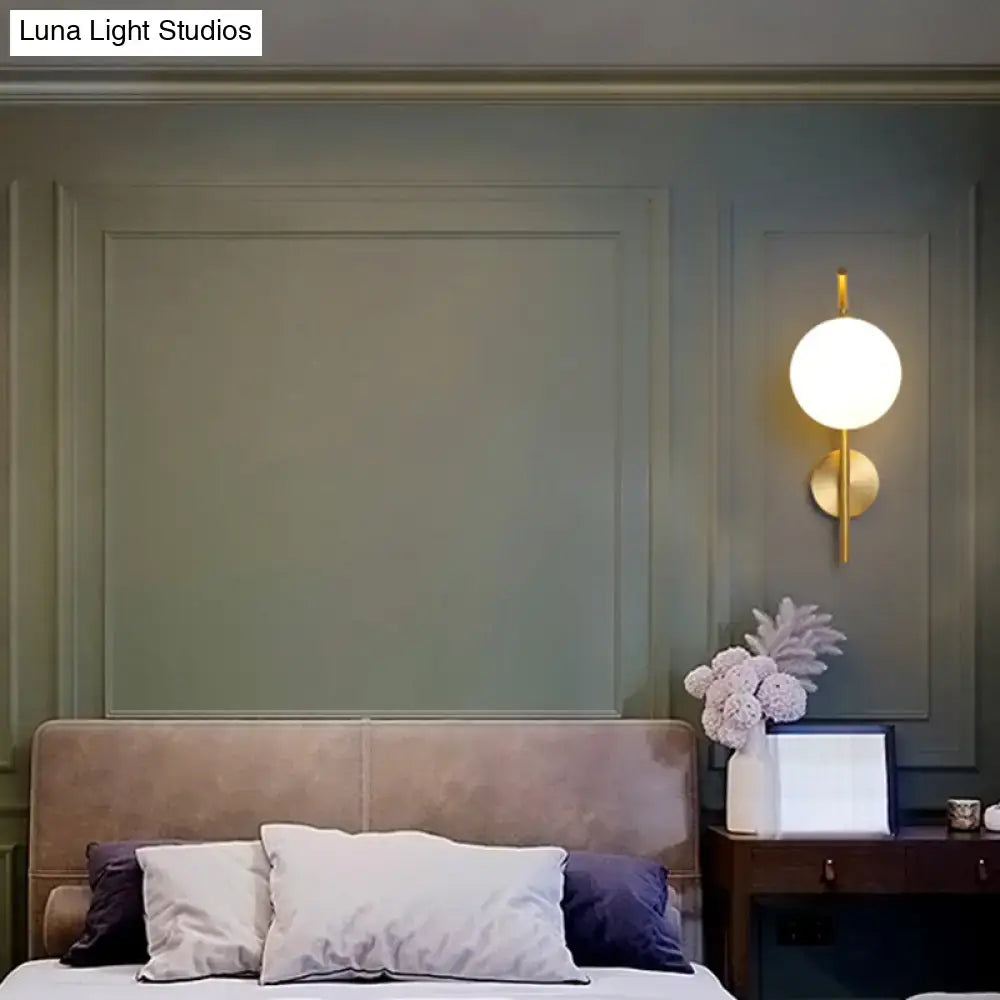 Gold-toned postmodern brass wall sconce with white glass geometric spherical design for living room lighting