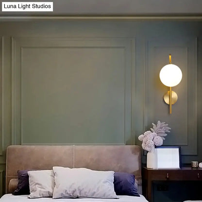 Gold-toned postmodern brass wall sconce with white glass geometric spherical design for living room lighting