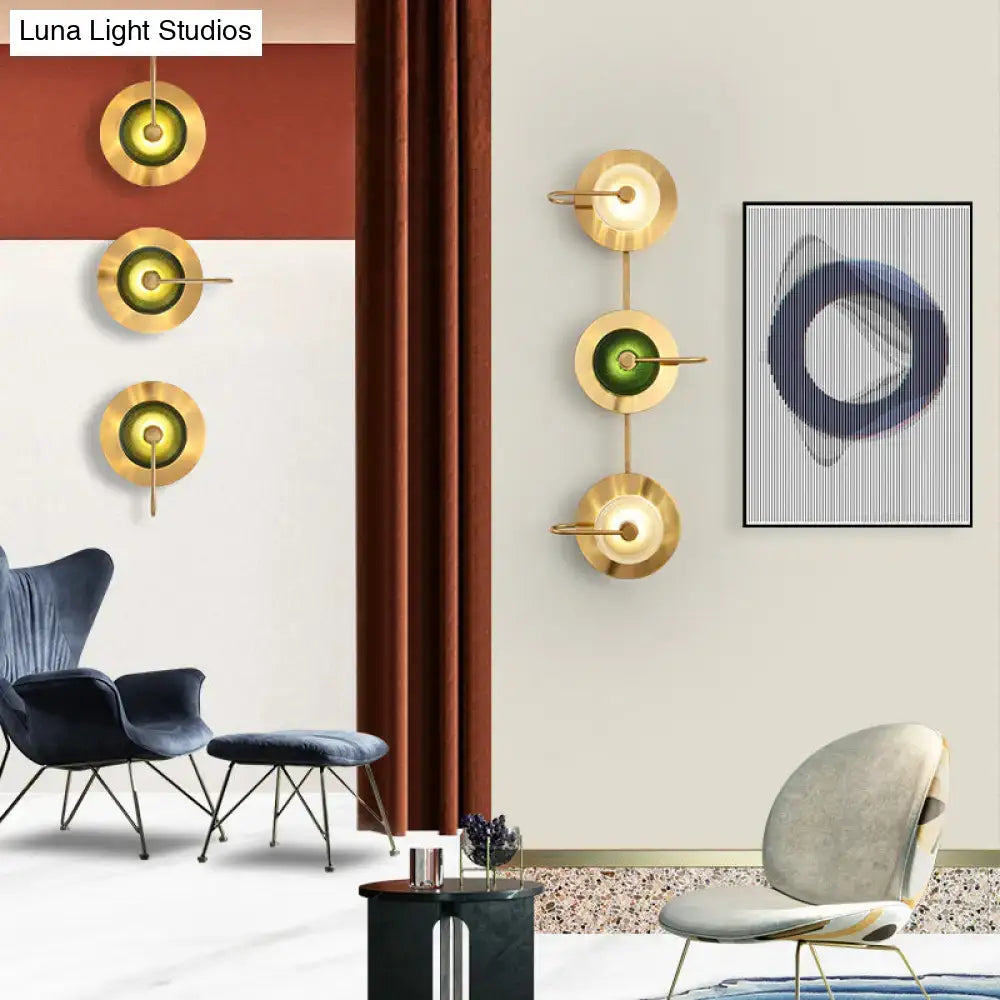 Postmodern gold wall sconce with olive glass disc and minimalist design as a wall mounted lamp for living room