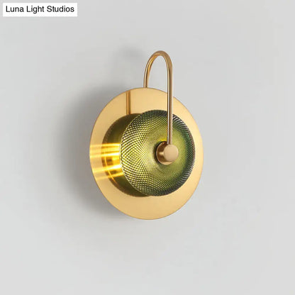 Postmodern gold wall sconce with olive textured glass disc diffuser and curved metal arm wall mounted lamp
