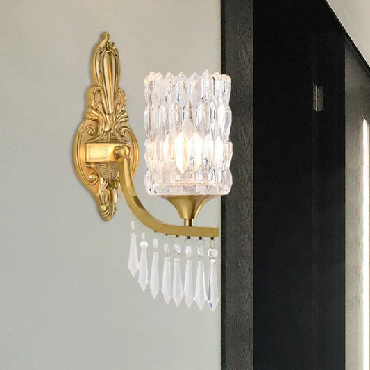 Postmodern gold column wall lamp with ornate design, faceted crystal shade, and dangling teardrop crystals for bedroom lighting