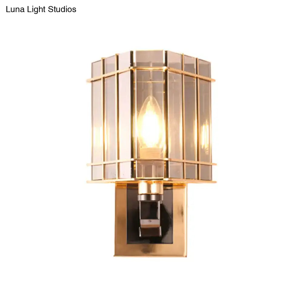 Postmodern gold-toned wall light with geometric glass shade and brass frame featuring illuminated filament bulb for living space