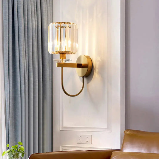 Gold-toned DecorBites™ postmodern wall sconce with cylindrical crystal shade and elegant curved arm design
