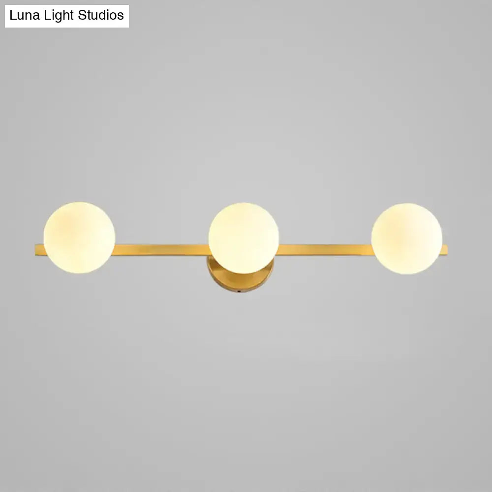 Postmodern gold-toned wall sconce with three frosted glass globe shades and 11in fixture height for bathroom use