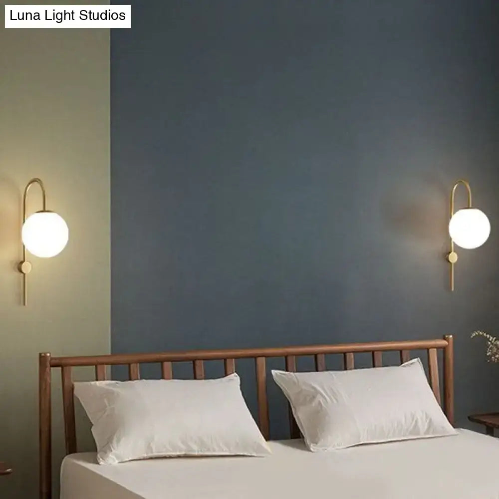 Postmodern gold-toned wall lamp with gooseneck arm and cream glass globe shades for bedroom lighting