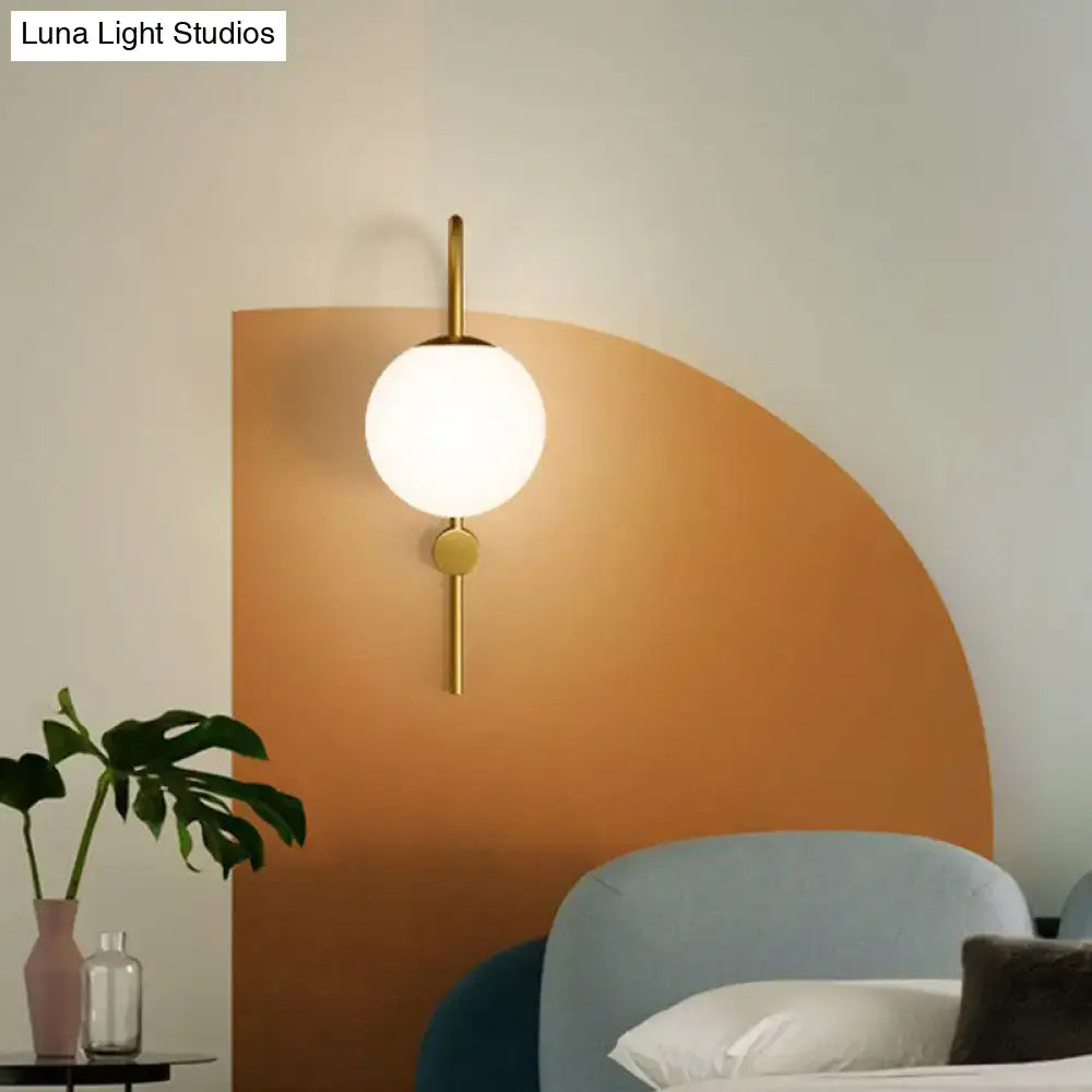 Postmodern gold wall lamp with gooseneck arm and cream glass globe in minimalist spherical metal frame
