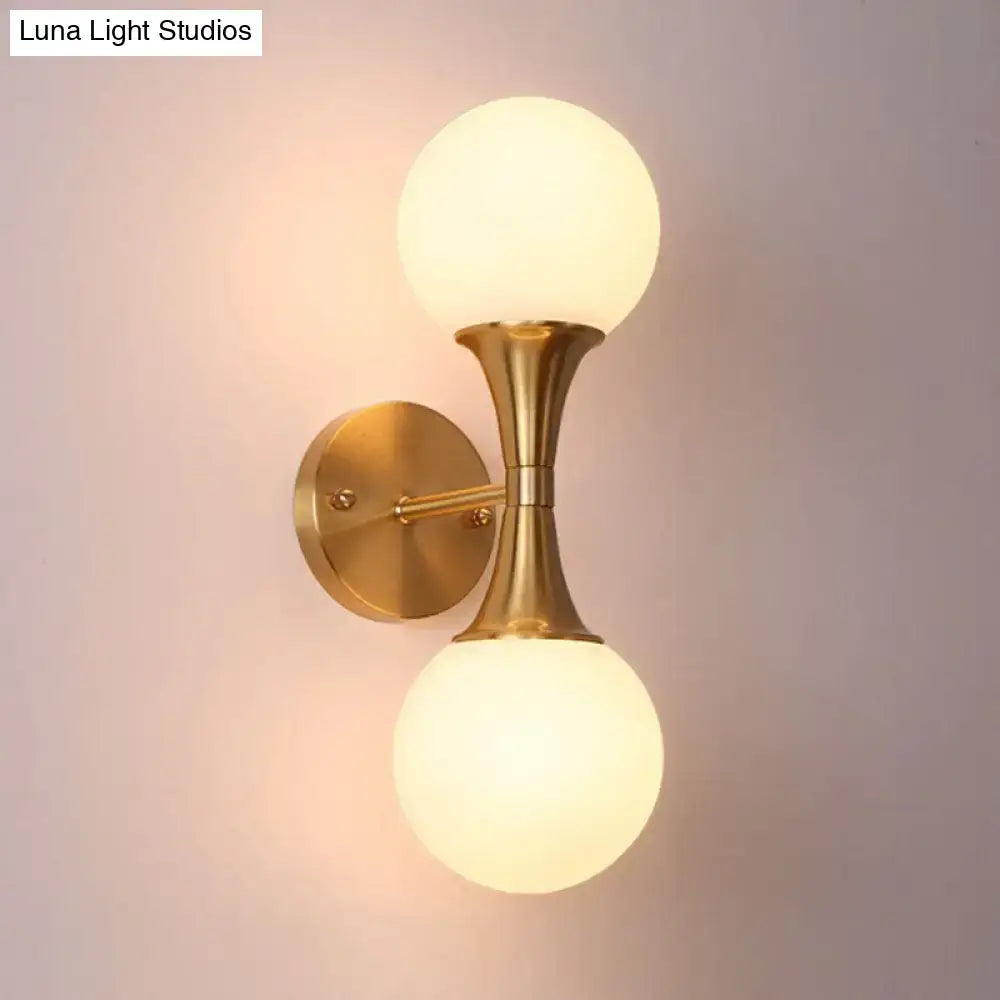 Postmodern gold-toned wall sconce light with two frosted milk glass globe shades for living room wall lamp