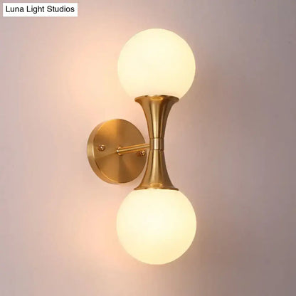 Postmodern gold-toned wall sconce light with two frosted milk glass globe shades for living room wall lamp