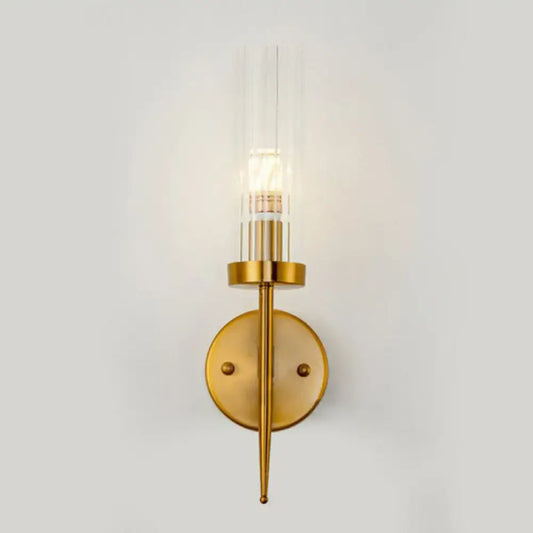 Postmodern gold-toned wall sconce with clear ribbed glass cylinder and slender metallic stem for stairway lighting