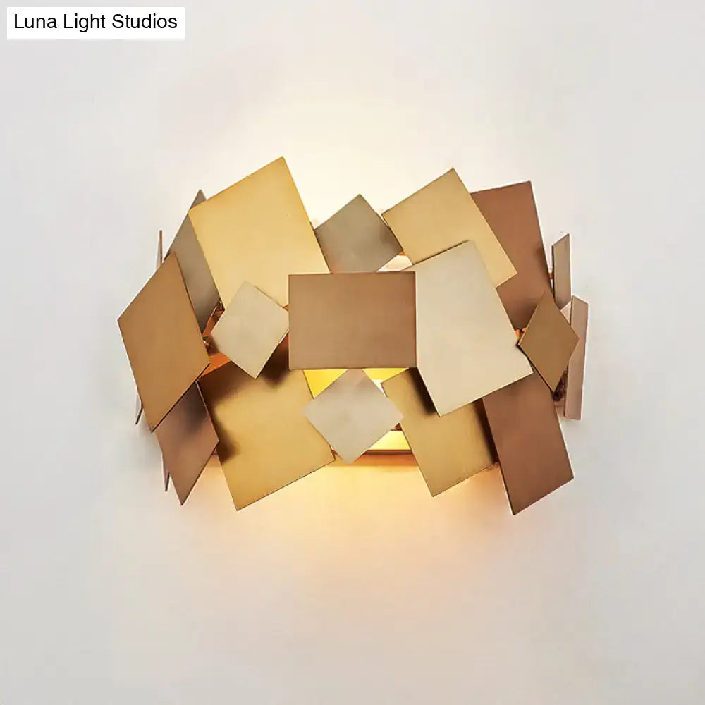 Modern gold-toned sconce light fixture with geometric overlapping square metal plates for living room use