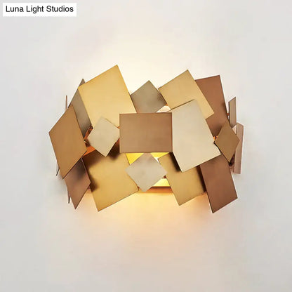 Modern gold-toned sconce light fixture with geometric overlapping square metal plates for living room use