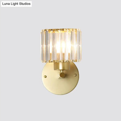 A modern wall lamp with a gold-finished metal base and a prismatic crystal shade for bedroom use
