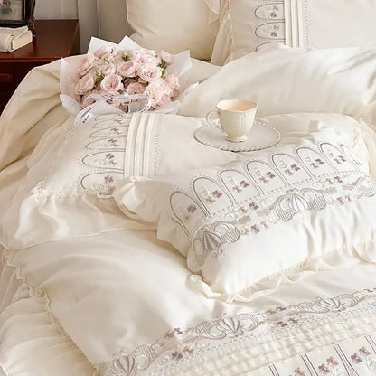 Cream-colored pillow with delicate lavender decorbites flowers embroidery and ruffled edges in princess wedding bedding set