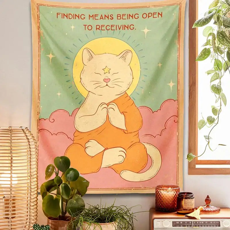 A soft green and pink decorbites cat tapestry featuring a meditating orange cat with a golden halo sun moon design