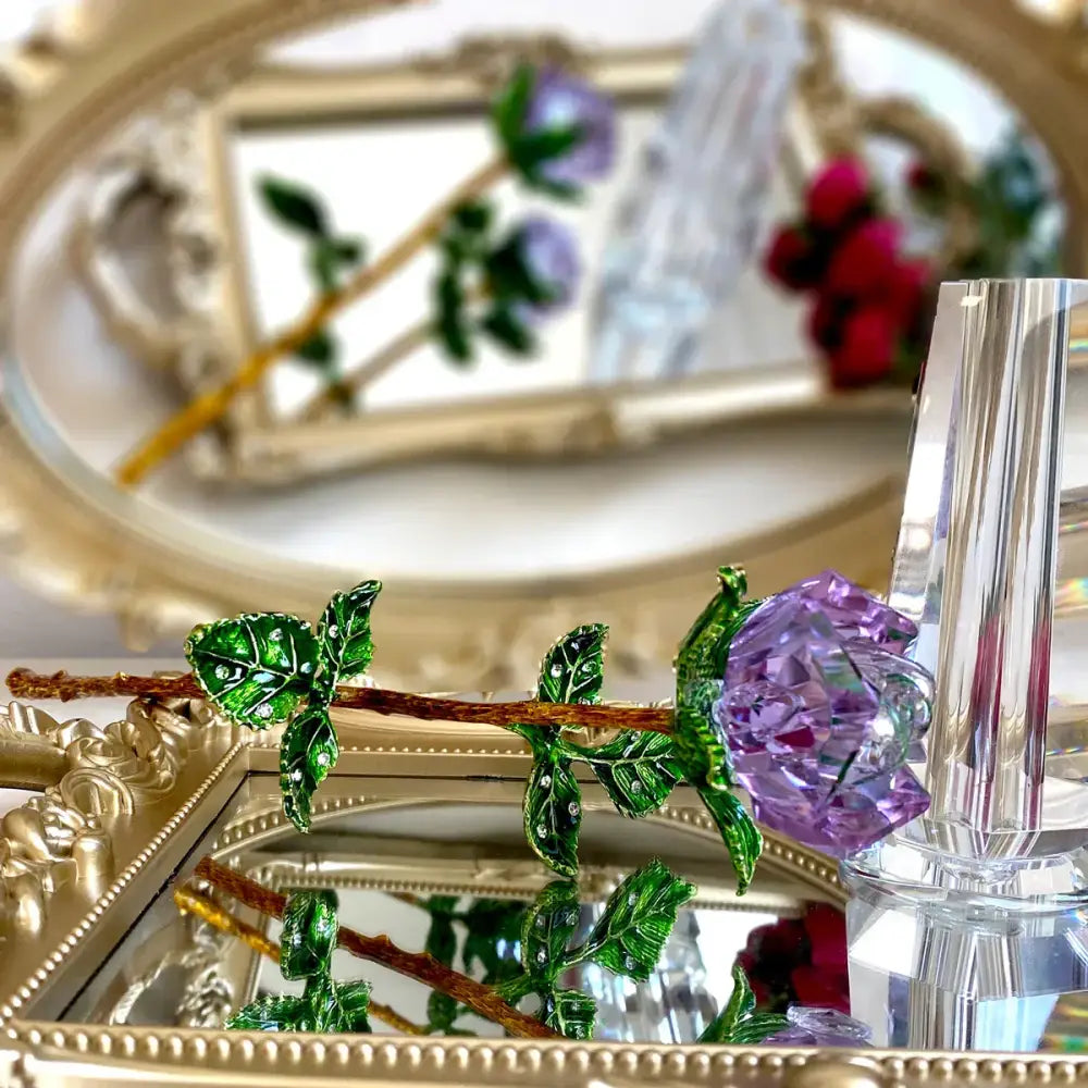 Purple and gold crystal rose figurine with sparkling purple crystal petals and green enamel leaves on a brown stem