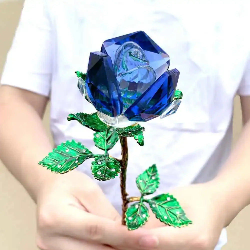 A vibrant blue crystal rose figurine with faceted petals and green enamel leaves on a metallic stem for living room decor