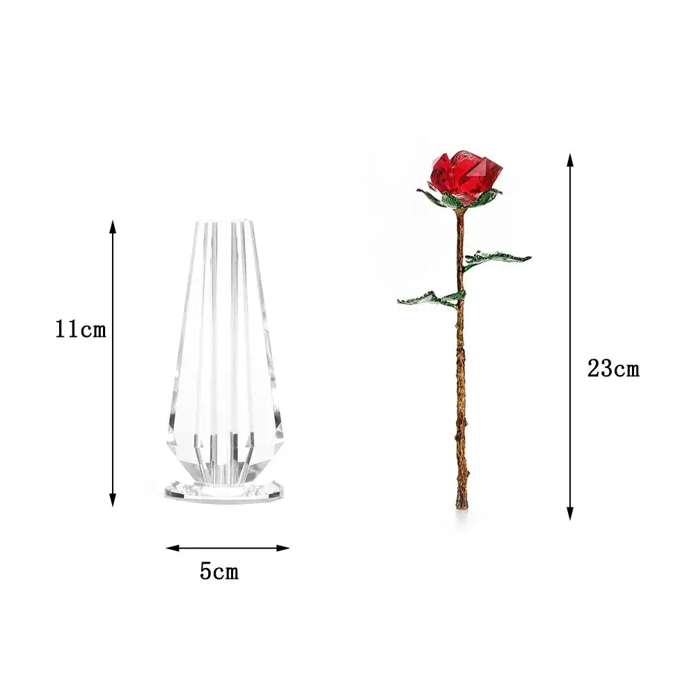 A sparkling red crystal rose figurine with gold stem and green leaves beside a clear glass vase for living room decor