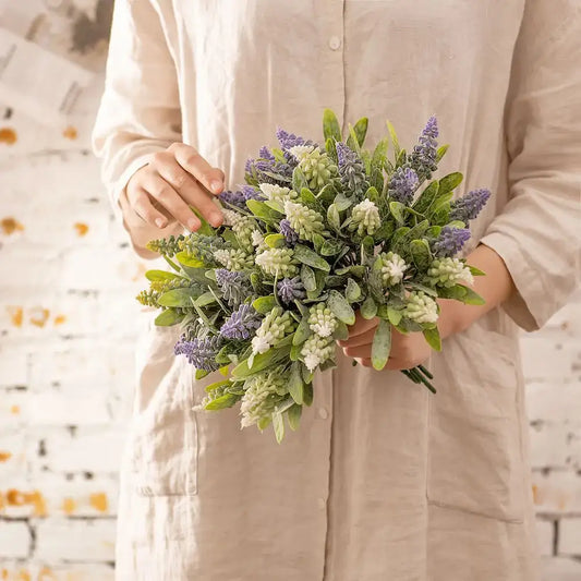 A delicate purple and white lavender fake green plants bouquet with frosted accents for wedding decor