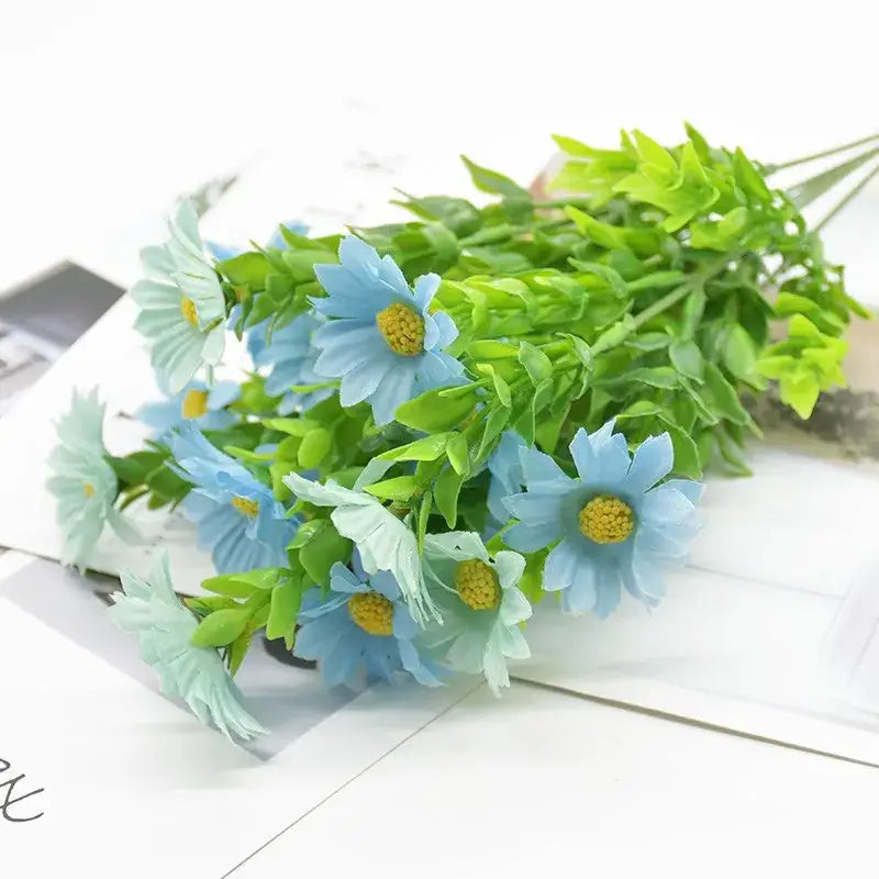 A bouquet of artificial light blue daisies with yellow centers and green plant synthetic stems for living room decor