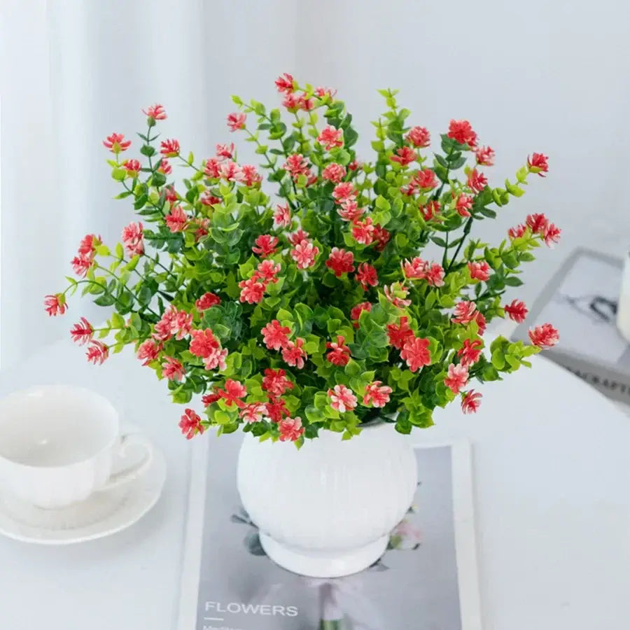 A vibrant purple decorbites artificial eucalyptus plant with pink blossoms in a white ceramic vase for decor