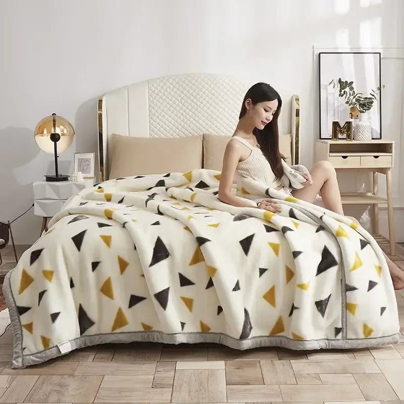 A cozy cream-colored double layer raschel blanket with black and mustard-yellow triangles and a soft gray border