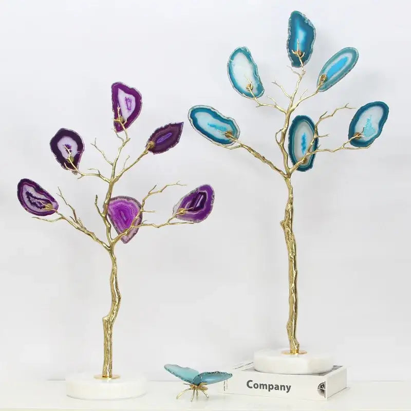 Two decorative purple and teal golden agate tree art piece sculptures with gold-toned branches on marble bases