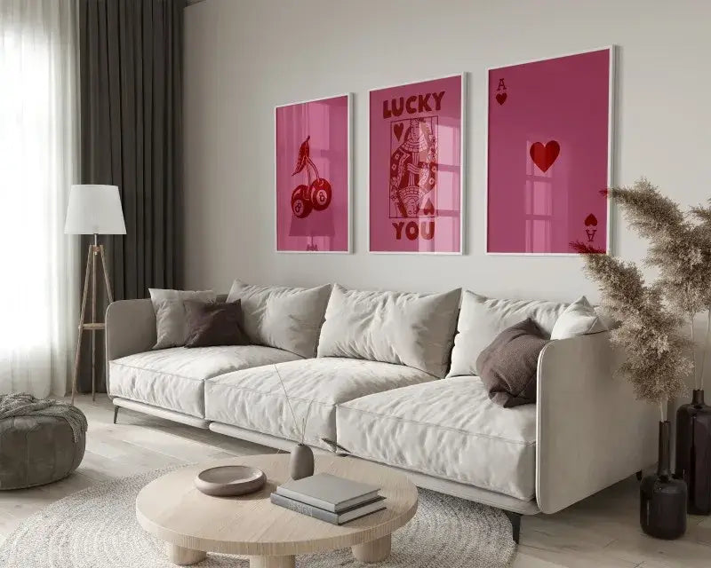Three framed pink playing card hearts wall art prints hang above a beige sofa in decorbites art set