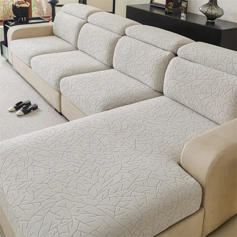 Quilted beige elastic sofa cover with subtle cracked-ice leaf pattern for living room seating protection