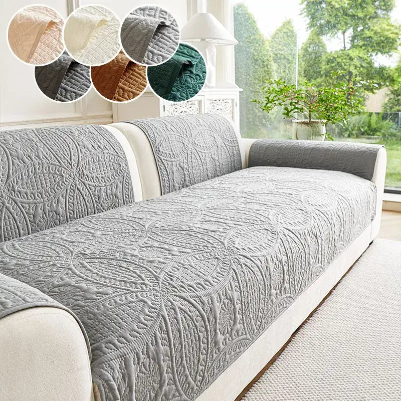 Gray quilted sofa cover with an intricate leaf pattern.