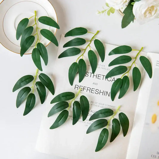 Realistic dark green silk willow leaves with glossy foliage arranged on white surface for wedding and home decor