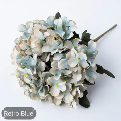 A delicate decorbites hydrangea branch decor featuring realistic blue artificial petals and dark green leaves for wedding decor