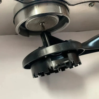 Black plastic and metallic bicycle chain tool with circular handle shown alongside red and white espresso machine cleaning brush