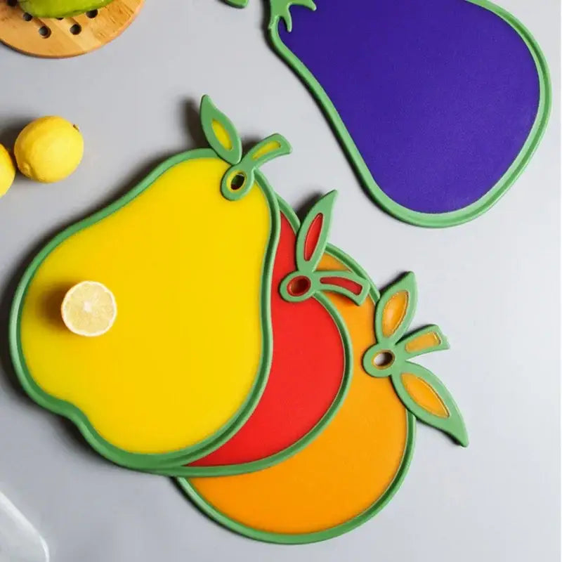 Bright yellow pear-shaped durable silicone cutting board with green trim and cutout stem detail for kitchen use