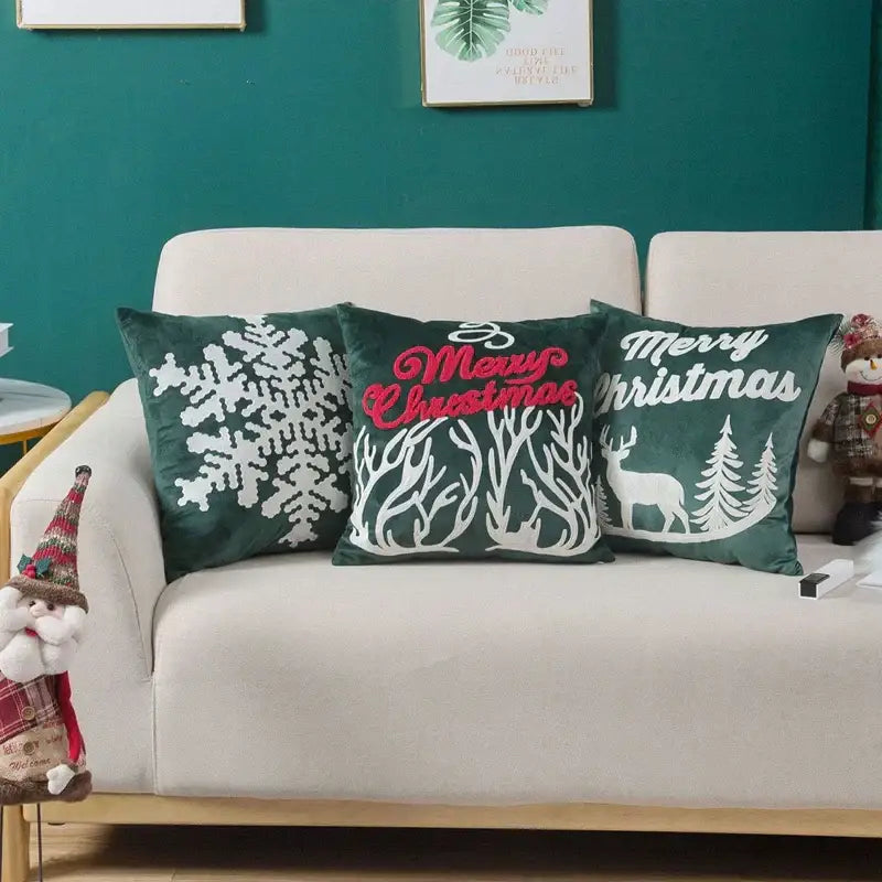 Three dark green velvet pillow covers with white embroidered christmas designs and red merry christmas lettering decorbites embroidered christmas pillow