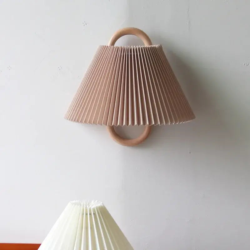 Soft blush pink pleated cream shade on a retro beech wood wall sconce wood wall lamp for bedroom use