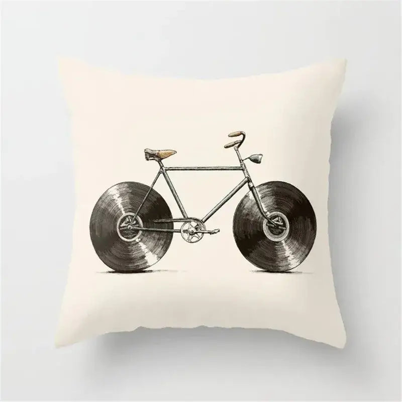 Cream-colored cushion cover with vintage-style bicycle and black camera print featuring vinyl record wheels for decor