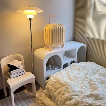 Cream-colored ribbed hard-shell suitcase with gold-tone wheels and handle shown alongside retro black glass shade led floor lamp