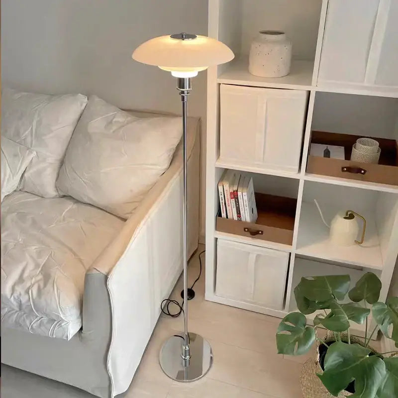 A sleek retro floor lamp with a black glass shade led emitting warm light in a modern living room setting