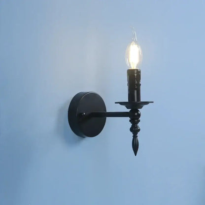 Retro black iron art wall lamp featuring a black wrought iron candlestick-style wall sconce with a glowing filament bulb