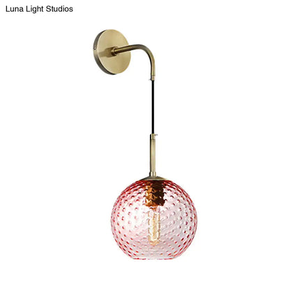 A delicate pink glass globe pendant light with bubble texture and brass hardware for pink yellow blue decor