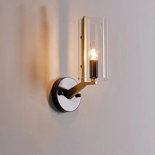 Retro brass and black wall light featuring a brass-finished transparent glass sconce with a clear cylindrical shade and exposed bulb