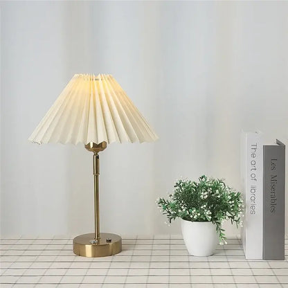 A cream-colored pleated table lamp with a brass-finished base from decorbites adjustable pleated collection