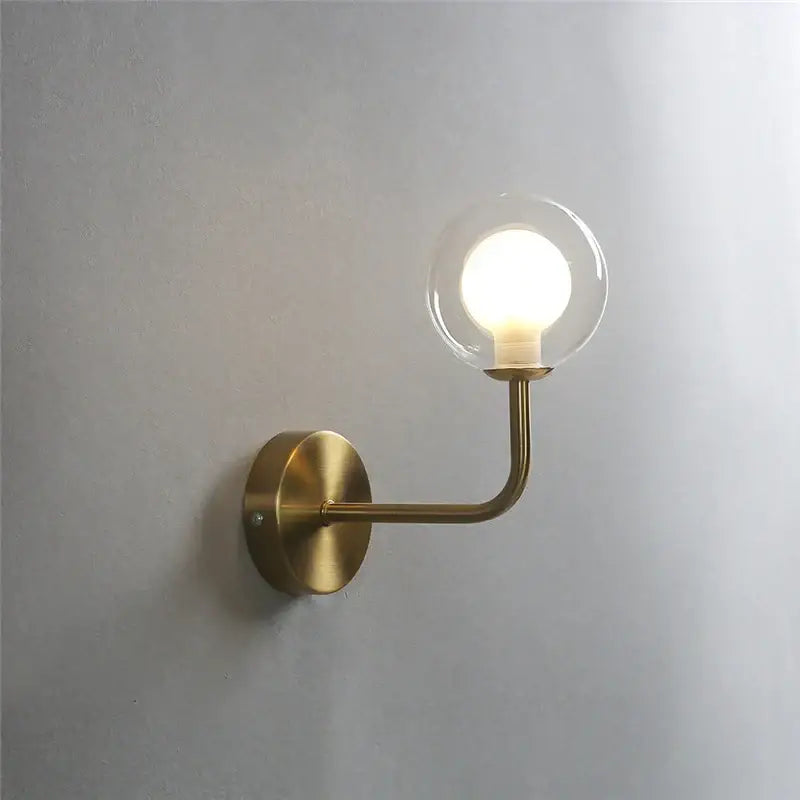 Retro brass curved wall lamp with a brass finish and clear glass ball featuring an illuminated bulb for bedroom decorbites wall lamp